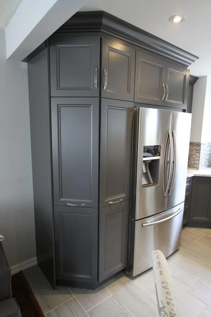 Modern kitchen corner featuring dark gray cabinets and stainless steel French door refrigerator with water and ice dispenser, light tiled flooring, and recessed ceiling light