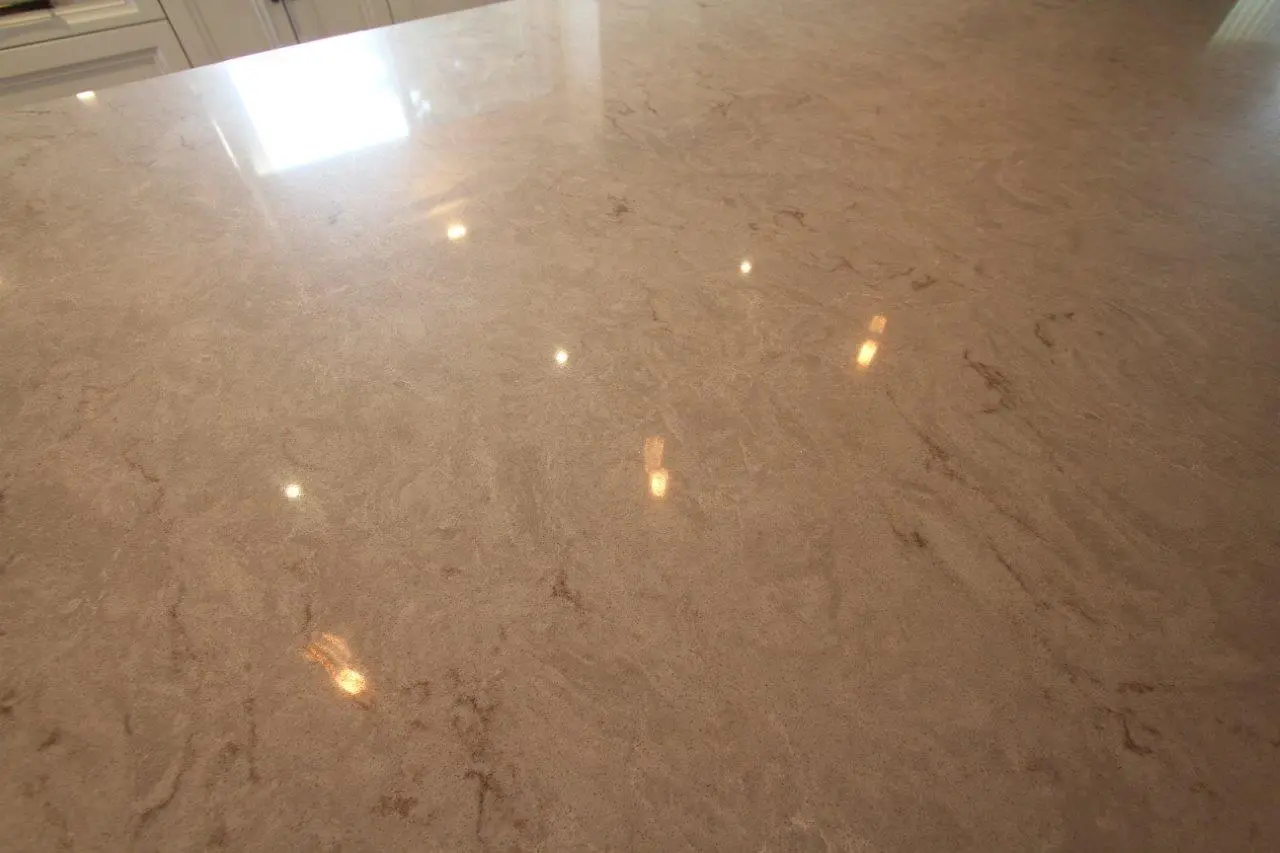 Smooth, polished beige marble countertop with natural veining and reflections of overhead lights.