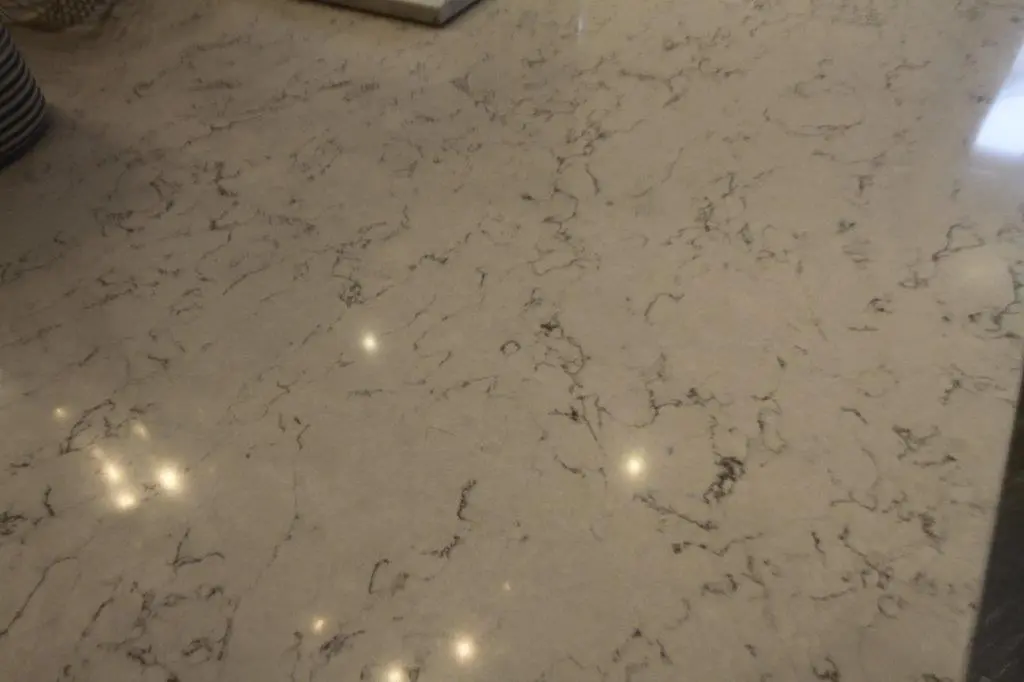 Cream-colored marble countertop with subtle dark veins and reflections of overhead lights