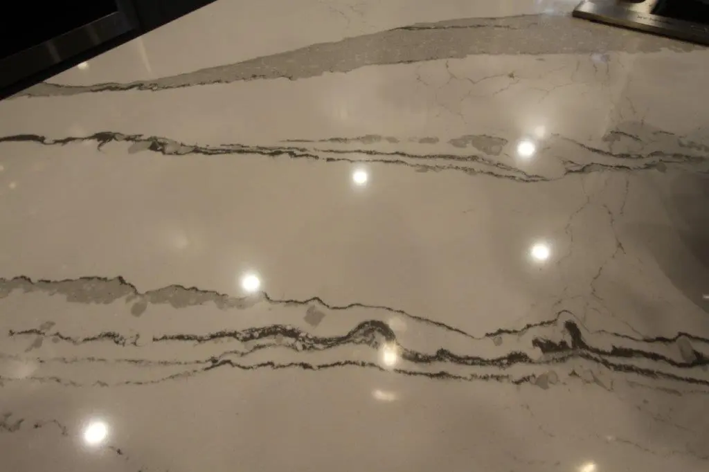 Close-up of a polished white marble surface with gray veining and light reflections.