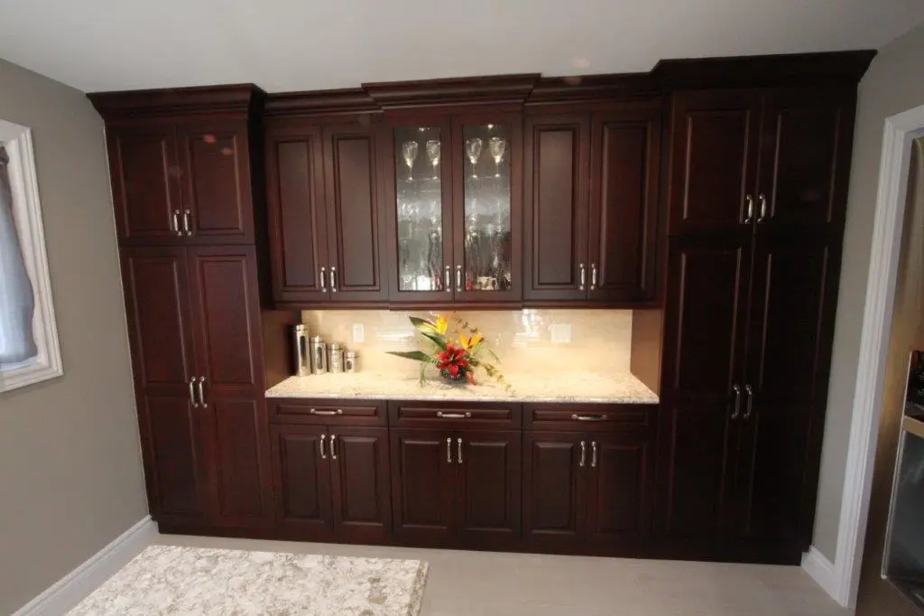 Kitchen cabinetry with dark wood finish, glass-paneled upper cabinet doors, marble countertop, and a floral arrangement in the center.
