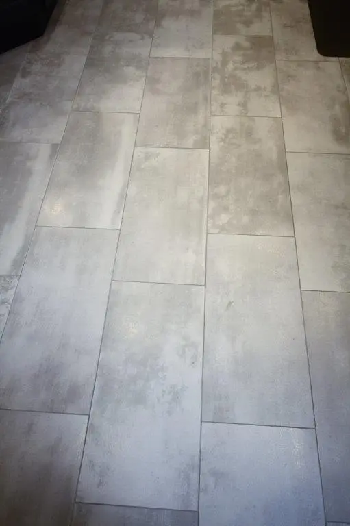 Light gray rectangular floor tiles with a subtle mottled texture arranged in a staggered pattern
