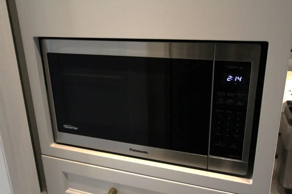 Built-in stainless steel Panasonic microwave oven with digital display installed in a white kitchen cabinet.