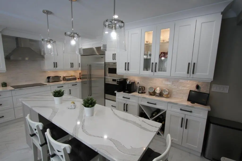 Modern kitchen with white cabinets, a quartz island countertop, stainless steel appliances, and pendant lighting.