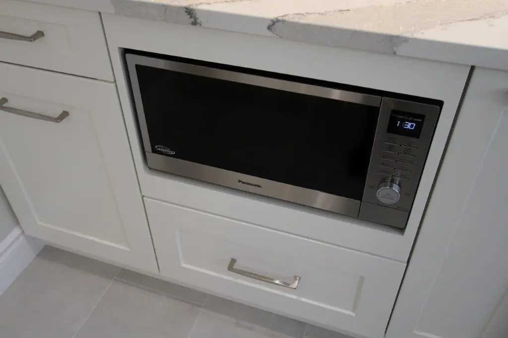 Built-in microwave with a stainless steel finish, installed within white kitchen cabinetry.