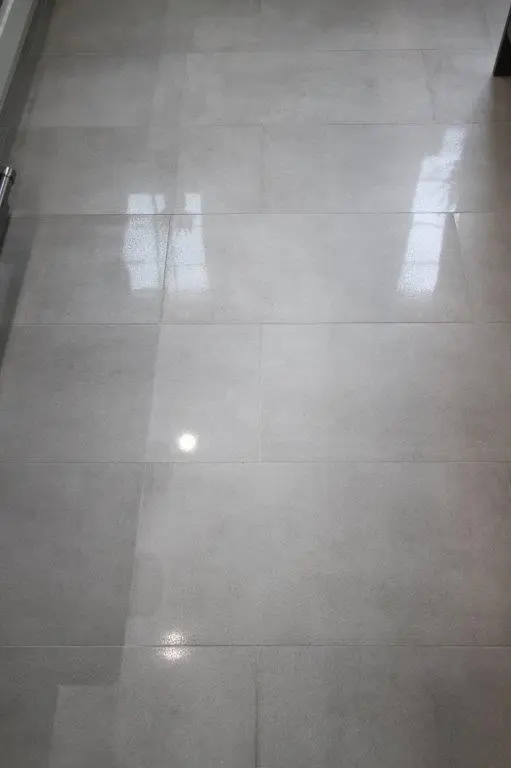 Smooth, polished light gray floor tiles with reflections from windows and lights above.