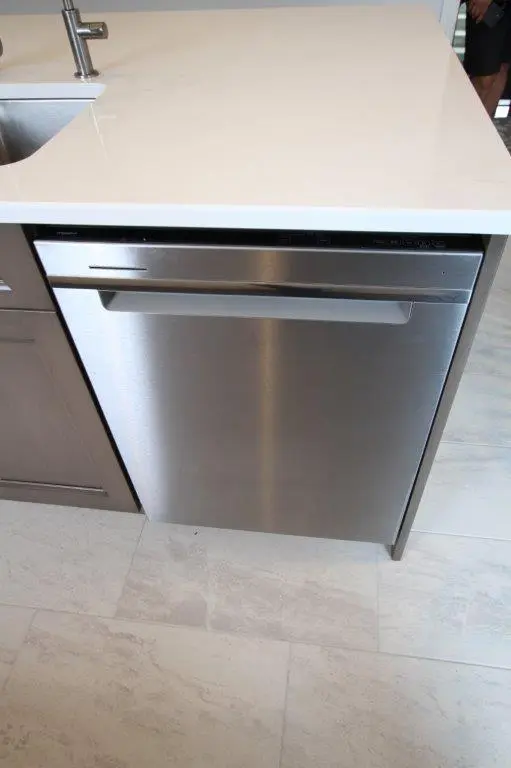 A stainless steel dishwasher integrated into a kitchen island with a white countertop.