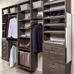 A modern walk-in closet with wooden shelving units, featuring hanging clothes, baskets, drawers, and shoes organized on shelves.