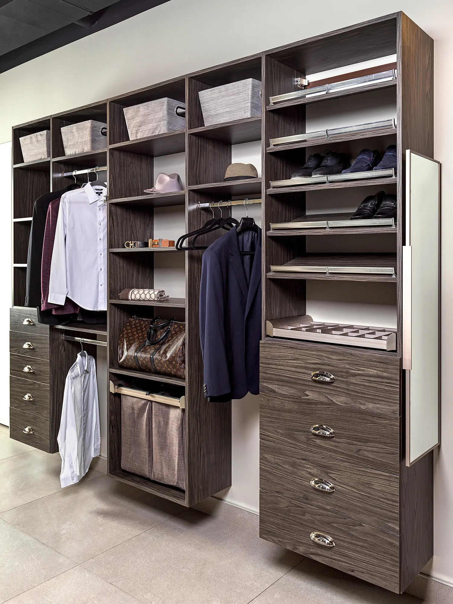 A modern walk-in closet with wooden shelving units, featuring hanging clothes, baskets, drawers, and shoes organized on shelves.