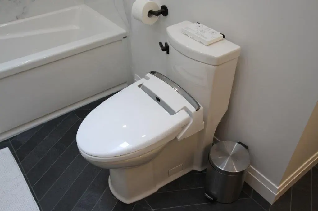 A modern toilet with an electronic bidet, located next to a bathtub.