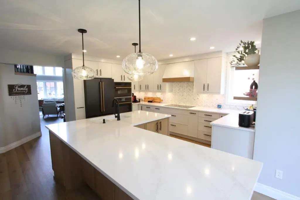 A modern kitchen with white cabinets, a quartz countertop, and two pendant lights hanging over the island.