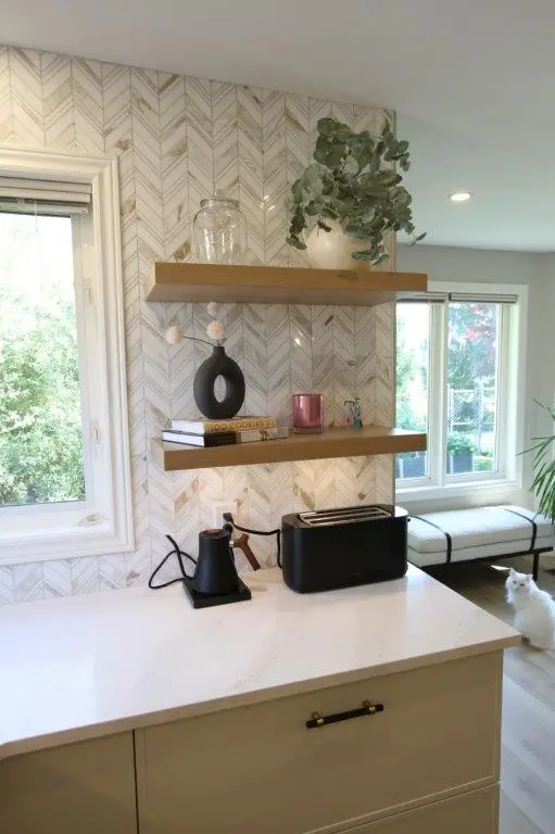 Modern kitchen with white quartz countertop, wood shelves holding decorative items, and geometric tile backsplash.