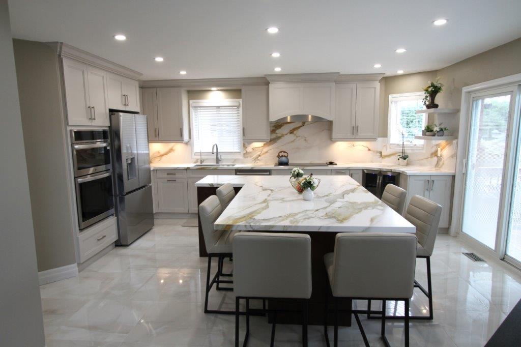 Modern kitchen with white cabinets, porcelain countertops, a large island with barstools, stainless steel appliances, and recessed lighting.