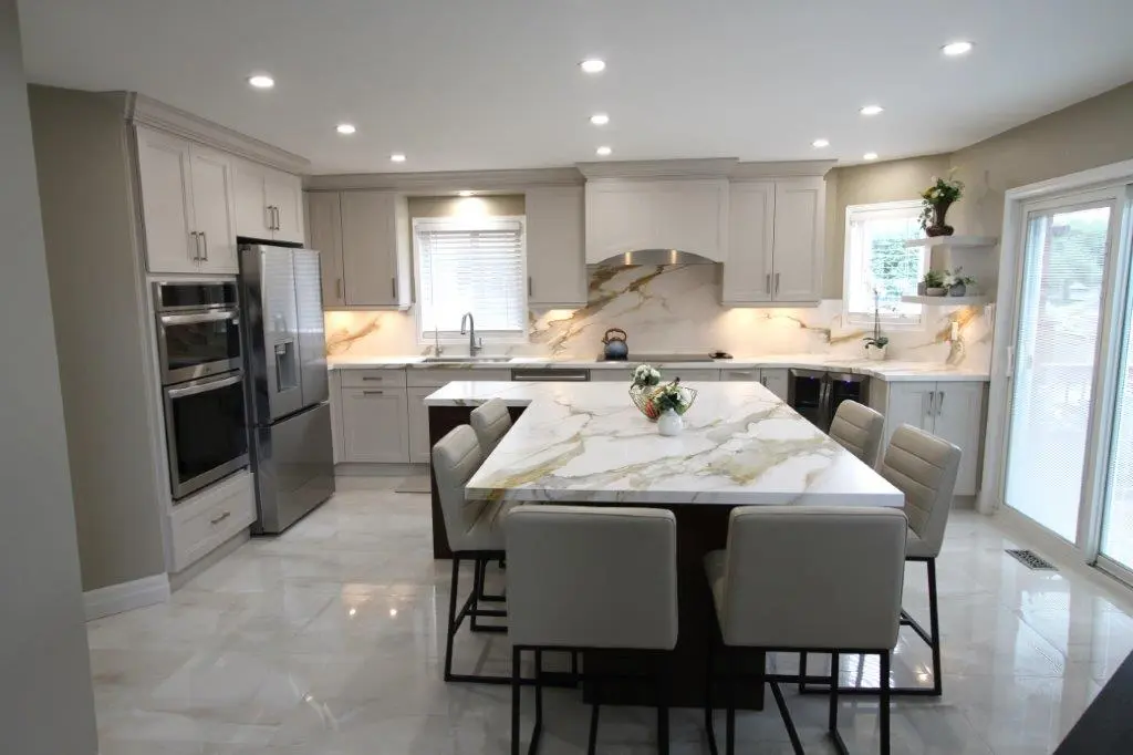 Modern kitchen with white cabinets, porcelain countertops, a large island with barstools, stainless steel appliances, and recessed lighting.