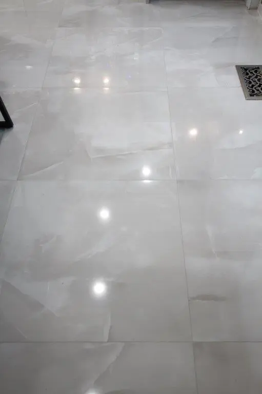 Shiny white porcelain floor tiles with soft lighting reflections.