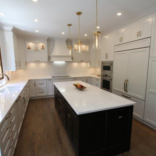 A modern kitchen with light-colored cabinetry, a large island with a dark base, stainless steel appliances, and pendant lighting over the island.