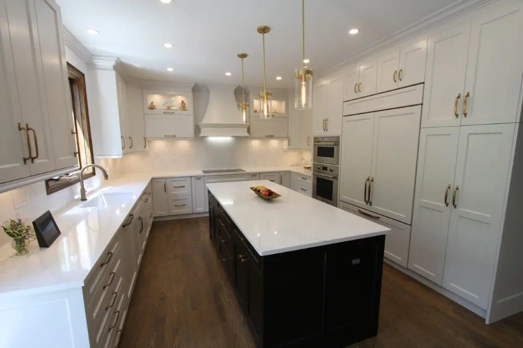 A modern kitchen with light-colored cabinetry, a large island with a dark base, stainless steel appliances, and pendant lighting over the island.