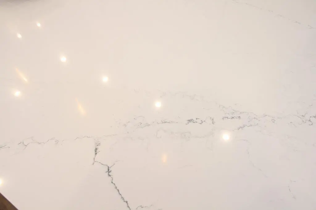 A smooth, reflective white quartz surface with subtle gray veining.