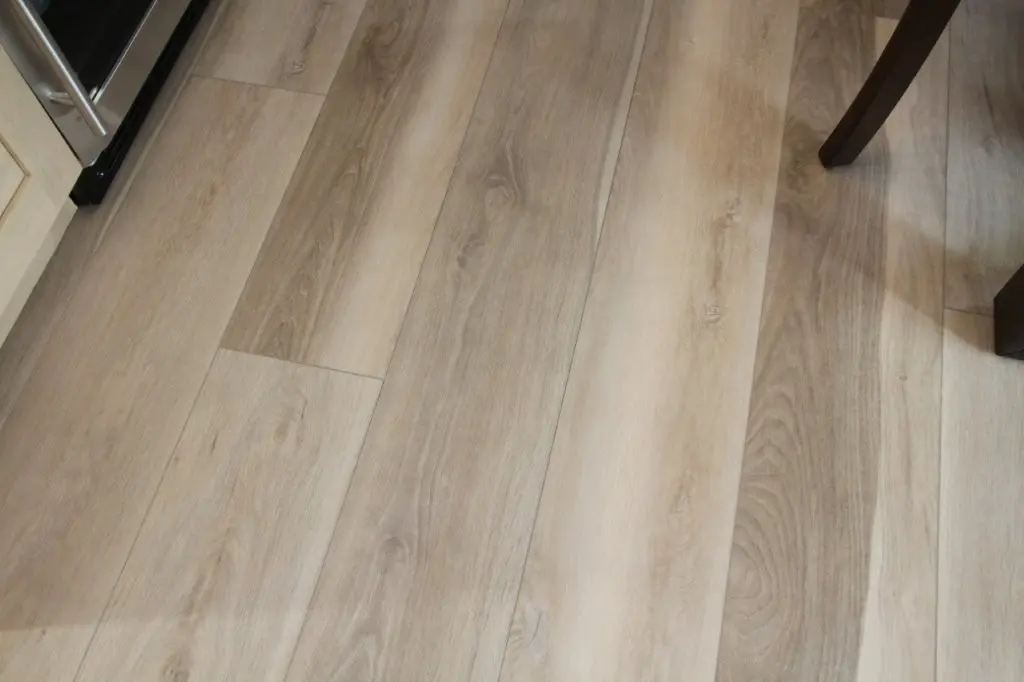 A close-up of a floor with light brown vinyl planks