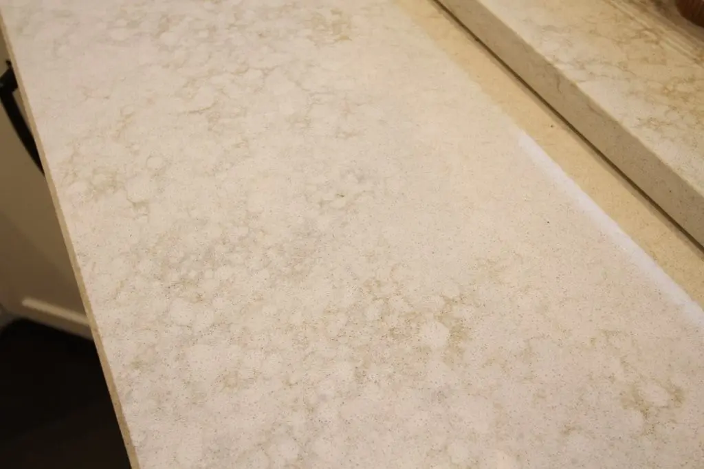 Close-up of a beige quartz countertop with subtle mottled patterns and a smooth polished surface.