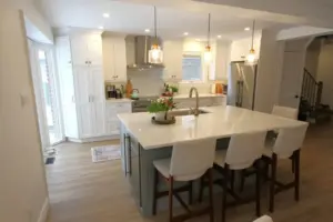 Bright modern kitchen with white cabinets, a large island, pendant lights, and four bar stools