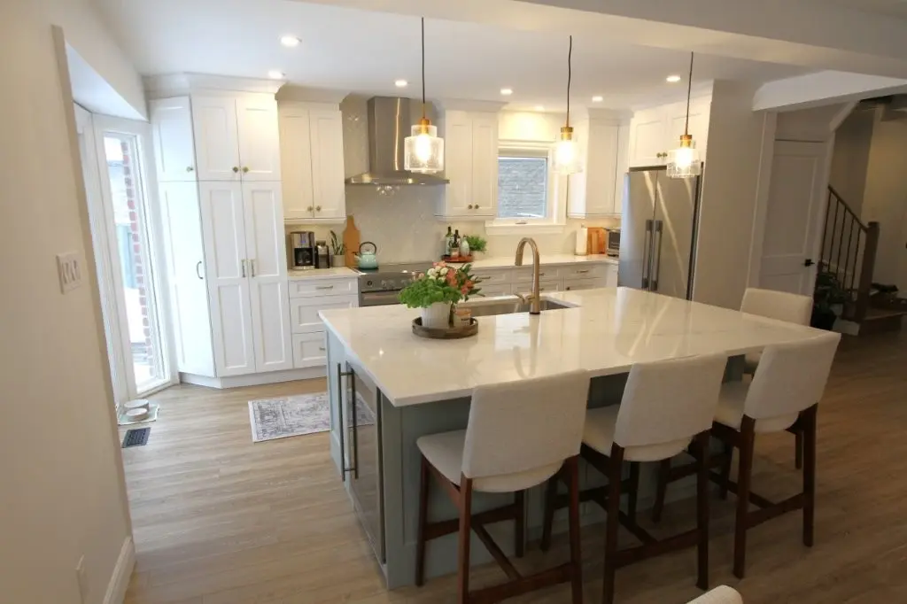 Bright modern kitchen with white cabinets, a large island, pendant lights, and four bar stools