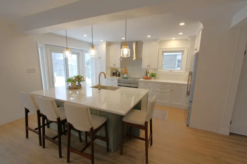 Bright modern kitchen with a large island, white cabinets, and four bar stools