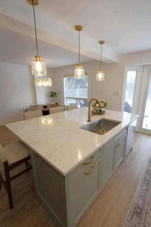 Bright kitchen with a large marble island, pendant lights, and a dining nook by the window