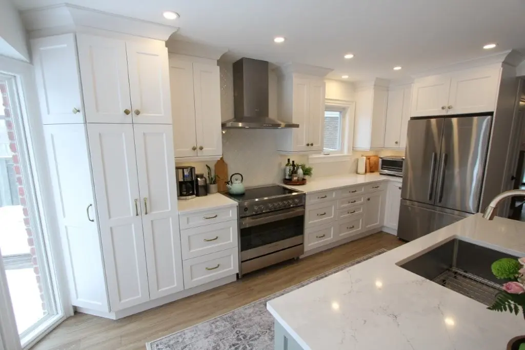 Bright white modern kitchen with stainless steel appliances, island sink, and hardwood floor