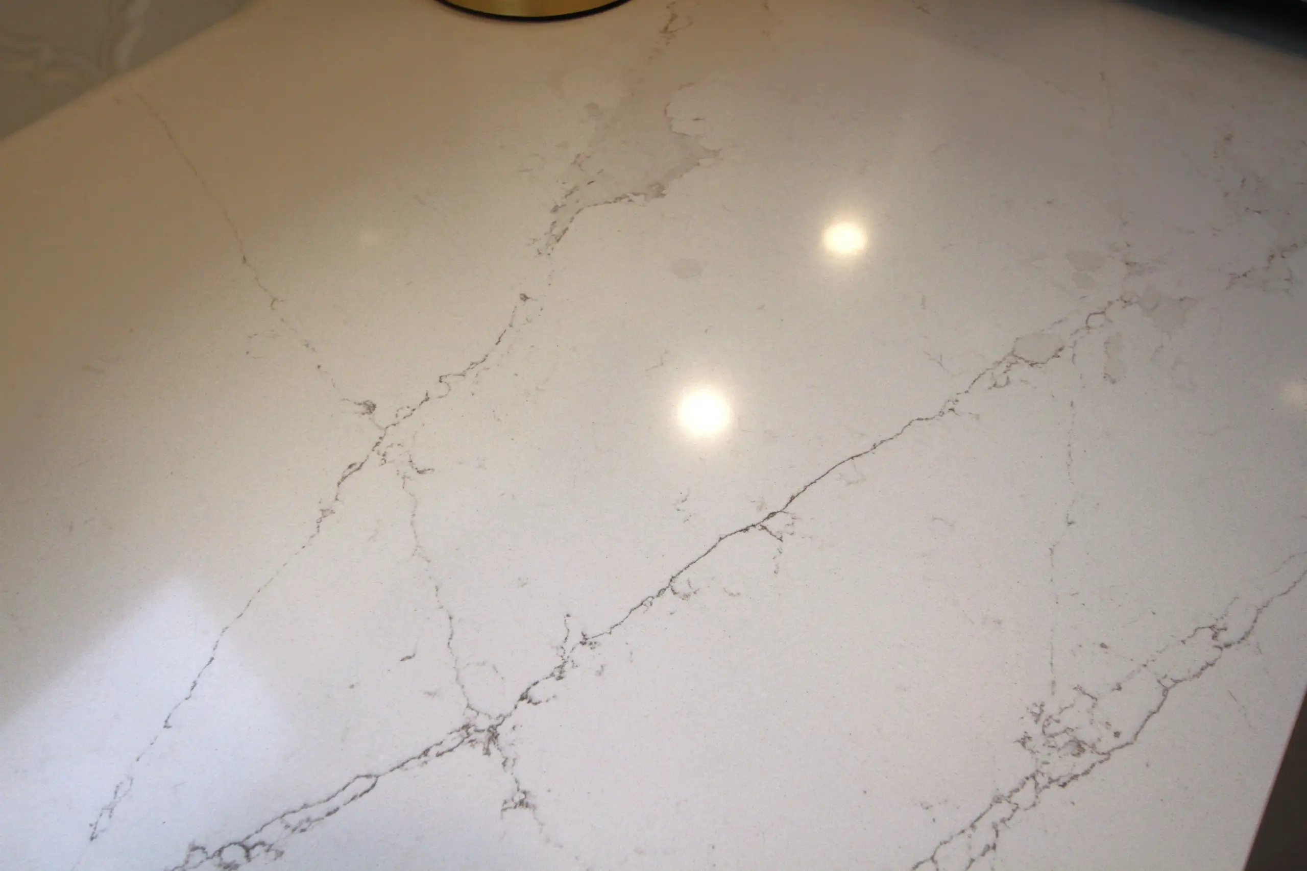 White marble countertop with gray veining and two light reflections