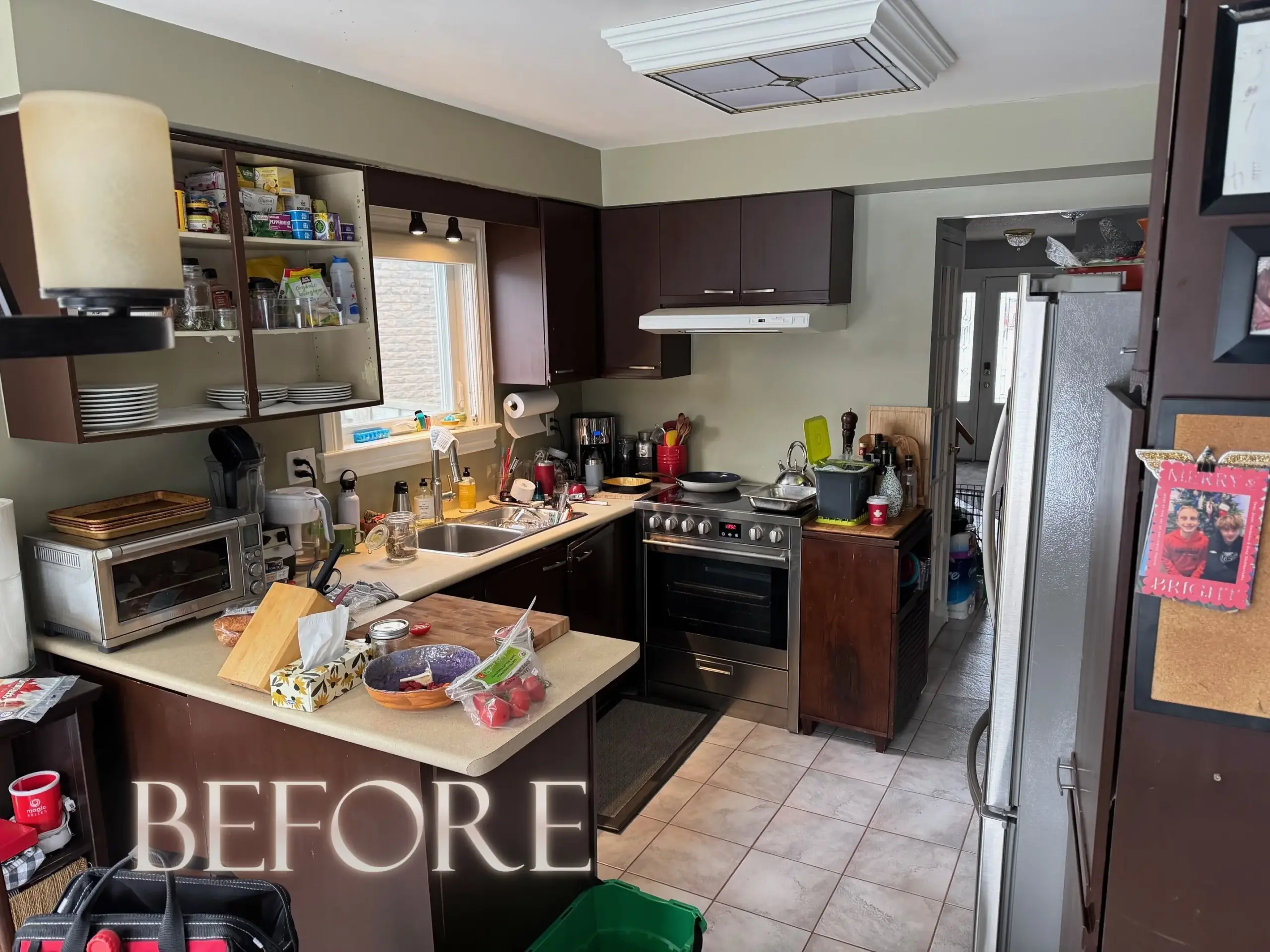 Cluttered kitchen with dark cabinets, open pantry shelves, a stove, and dishes on the counter, labeled “BEFORE”