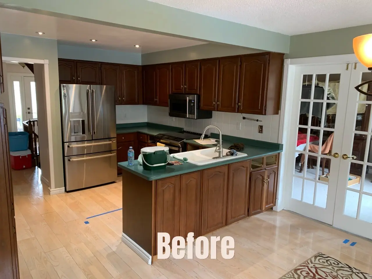 Kitchen with dark wood cabinets, stainless steel appliances, and a green island countertop labeled “Before”