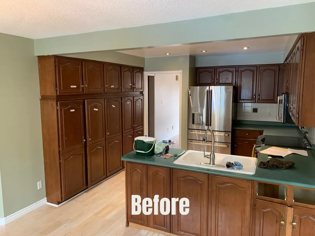 Kitchen with dark wood cabinets, green countertops, stainless-steel refrigerator, and “Before” text over the island
