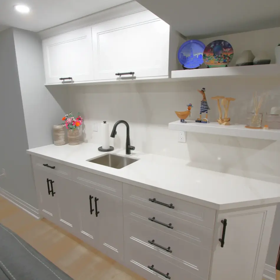 IMG_3926 Modern kitchenette with white cabinets, black faucet, open shelves, and decorative plates and plants