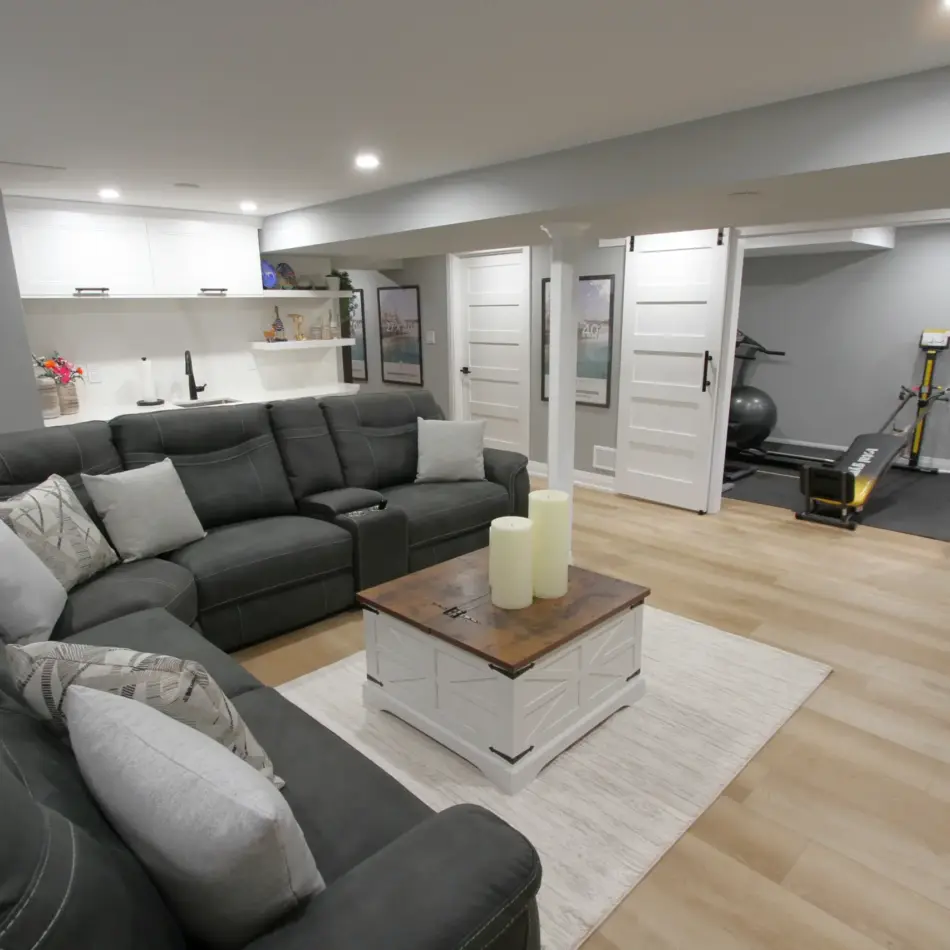 IMG_3945 Open-concept basement with a sectional sofa, coffee table, kitchenette, and a small home gym behind sliding doors