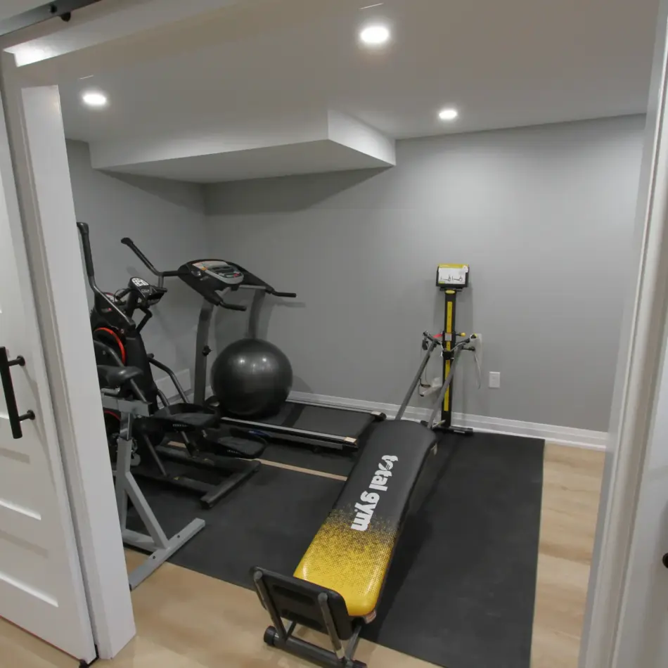 IMG_3975 Home gym with a treadmill, elliptical, exercise ball, rowing machine, and bench in a small room