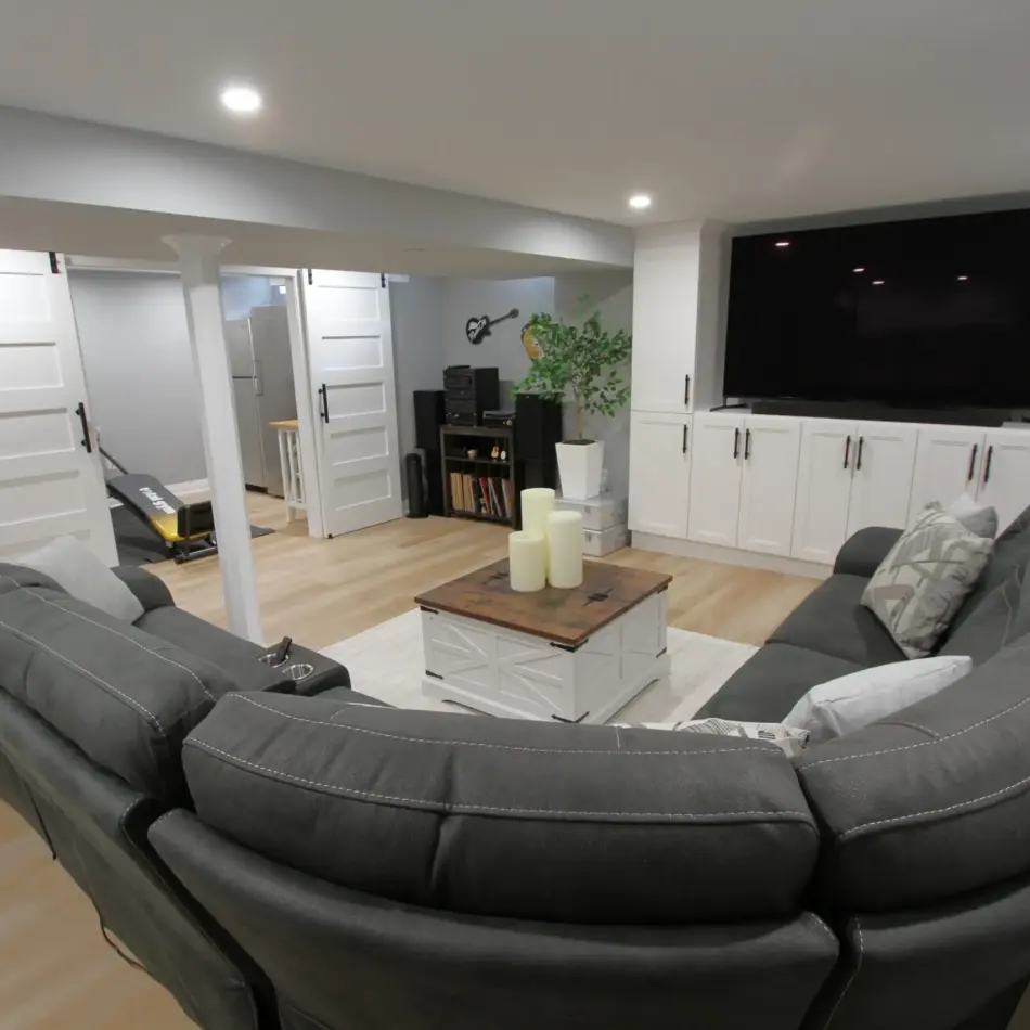 IMG_4000 Modern basement living room with a sectional sofa, large TV, white cabinets, and a coffee table on a light rug