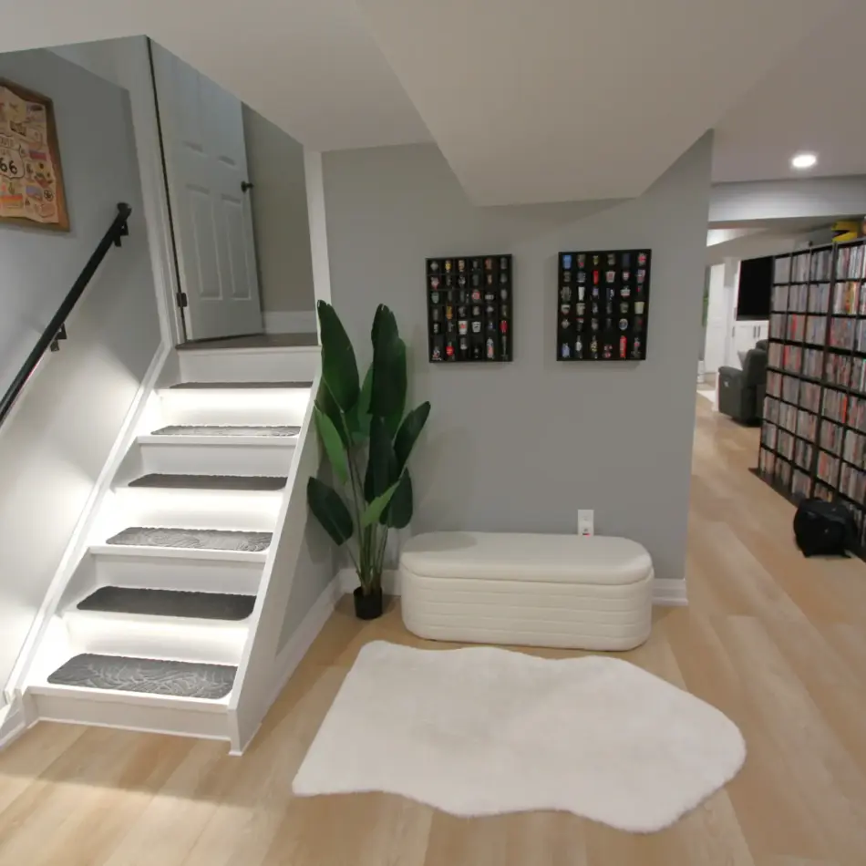 IMG_4029 Finished basement with lit stairs, display shelves, and a wall of movie discs beside a lounge area