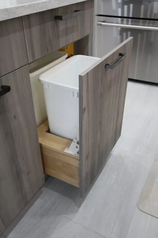 Pull-out kitchen cabinet trash bin with a white liner open inside a drawer