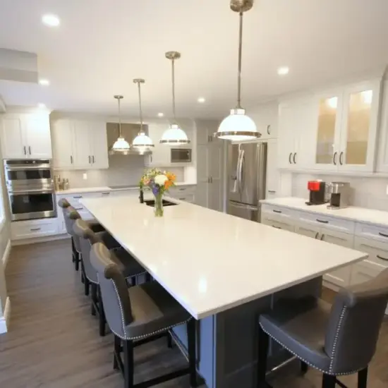 Modern white kitchen with a large island, pendant lights, and bar stools