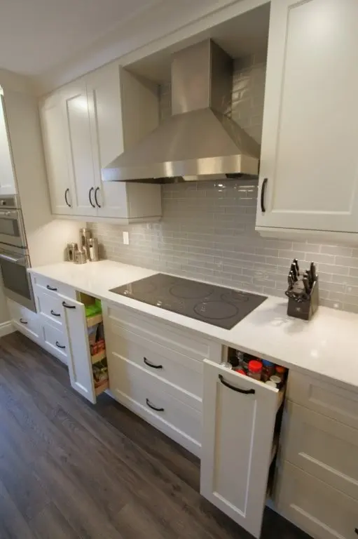 Kitchen with white cabinets, a stainless steel range hood, and an induction cooktop built into the counter