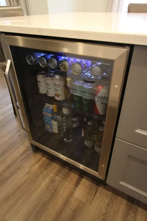 Under-counter beverage fridge stocked with canned and bottled drinks