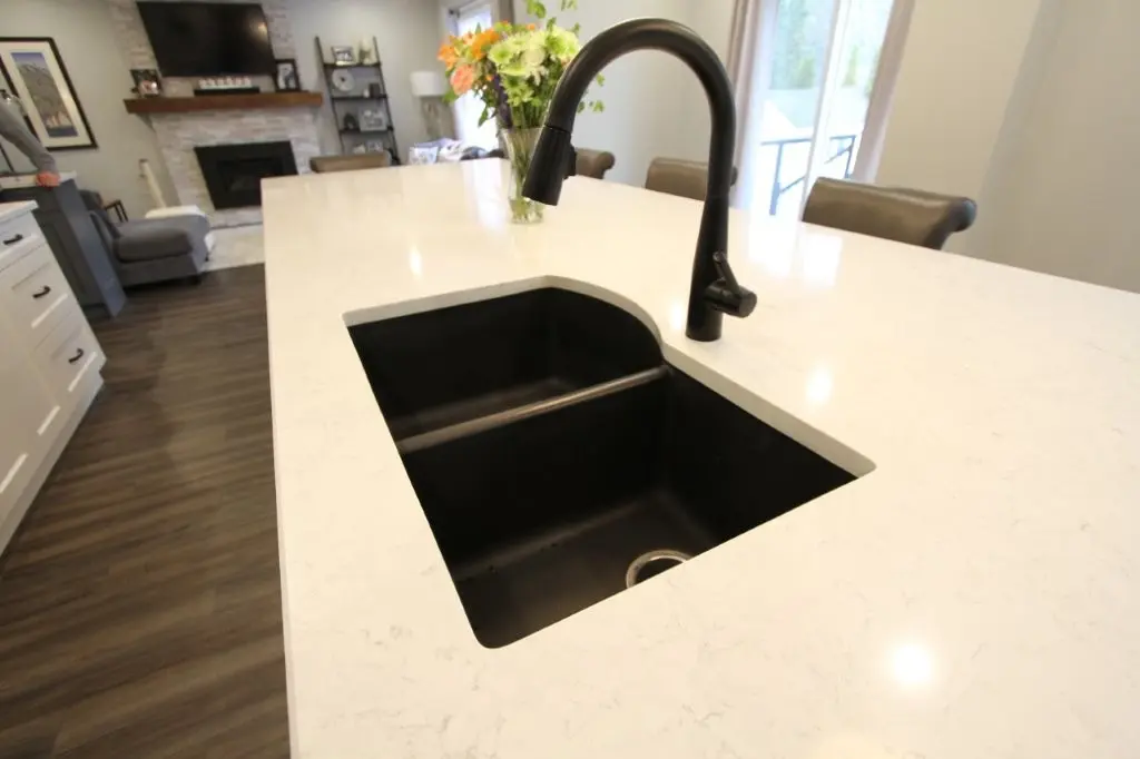 Modern kitchen island with a black sink and faucet in an open living room